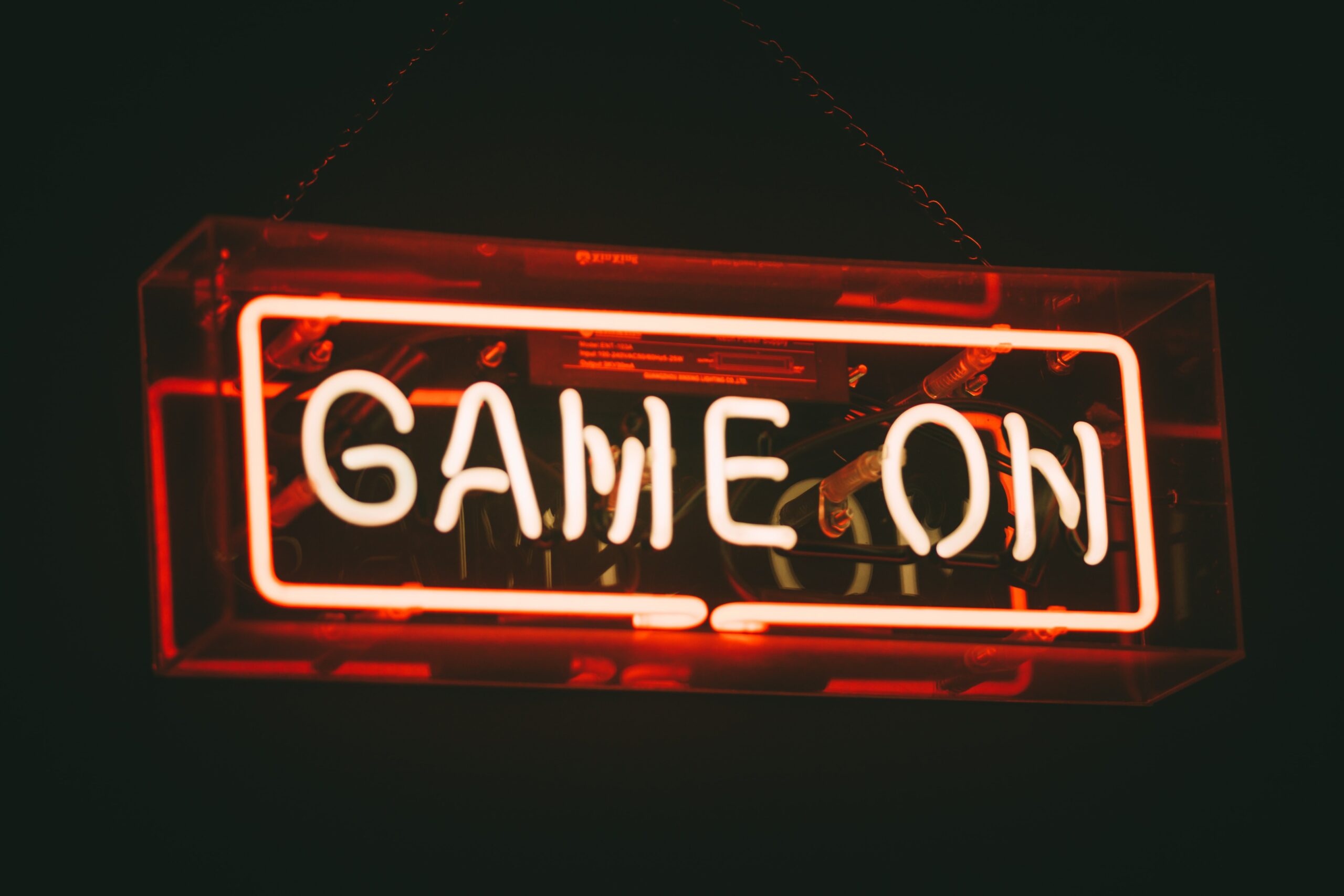 Red neon text on a black background: Game On