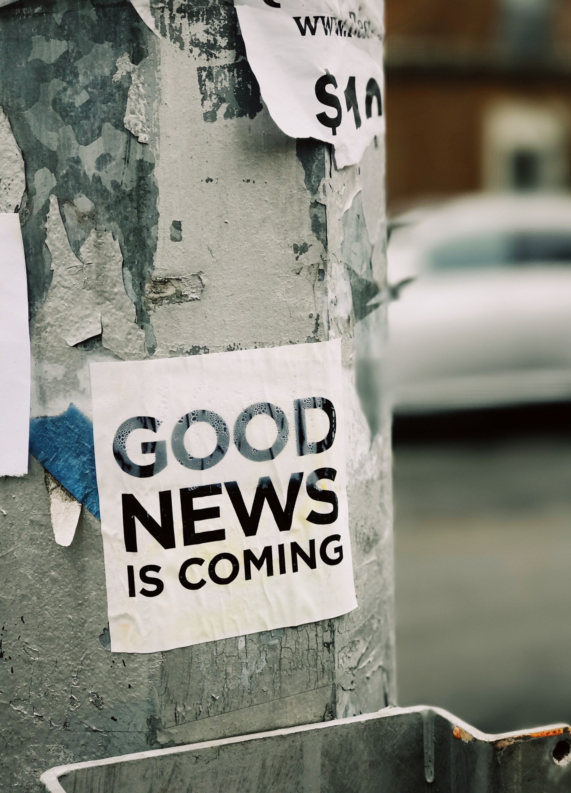 A pole has a poster on it that reads "Good news is coming."
